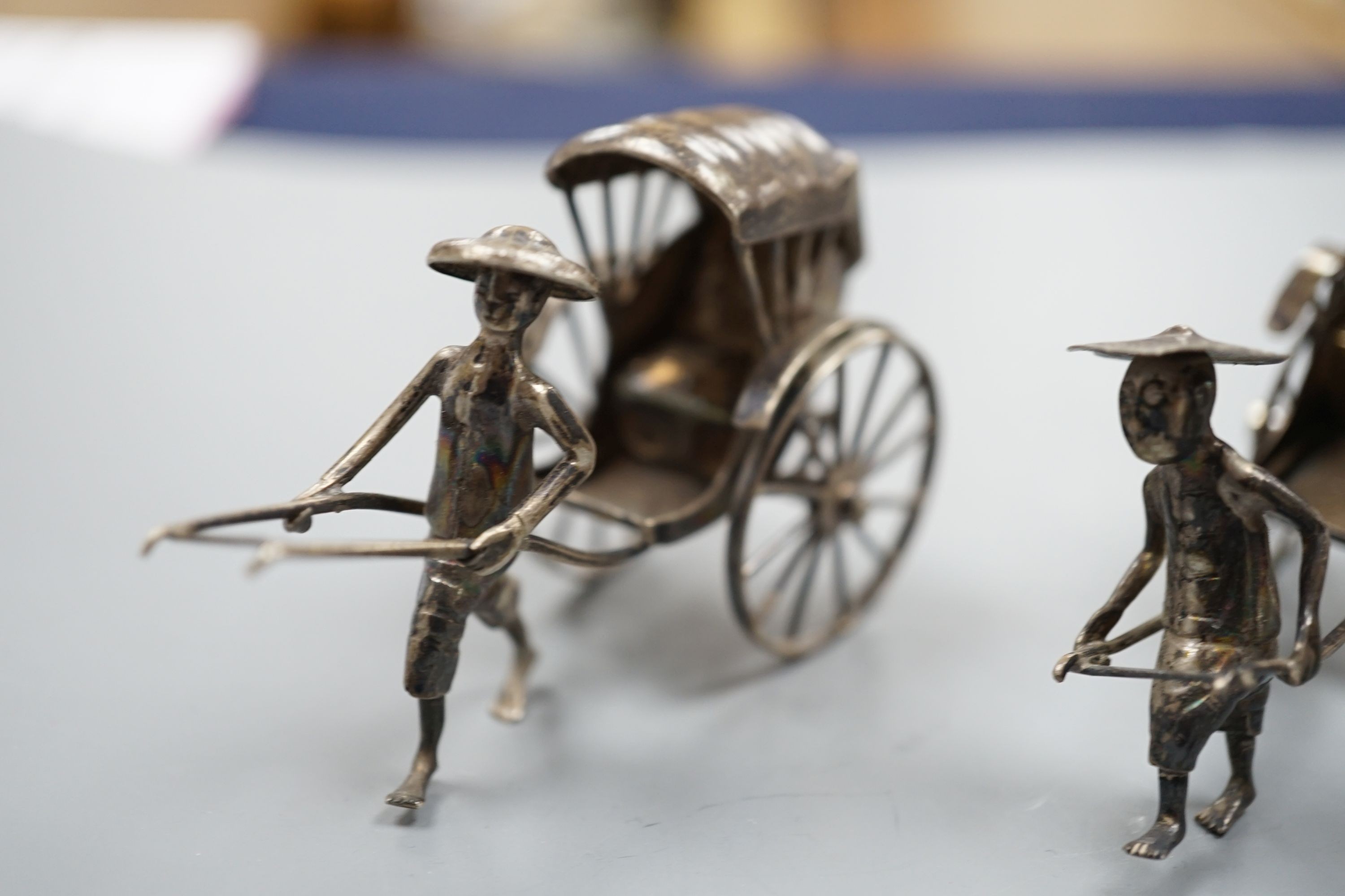 Two early 20th century miniature Chinese white metal models of a figure and rickshaw, by Wang Hing, length approx. 74mm. two other similar Chinese items and and unmarked miniature carriage.